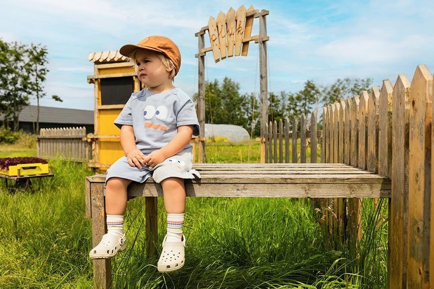 Jongen met een Sproet & Sprout Terry Bermuda Shorts Colourblock aan op bankje