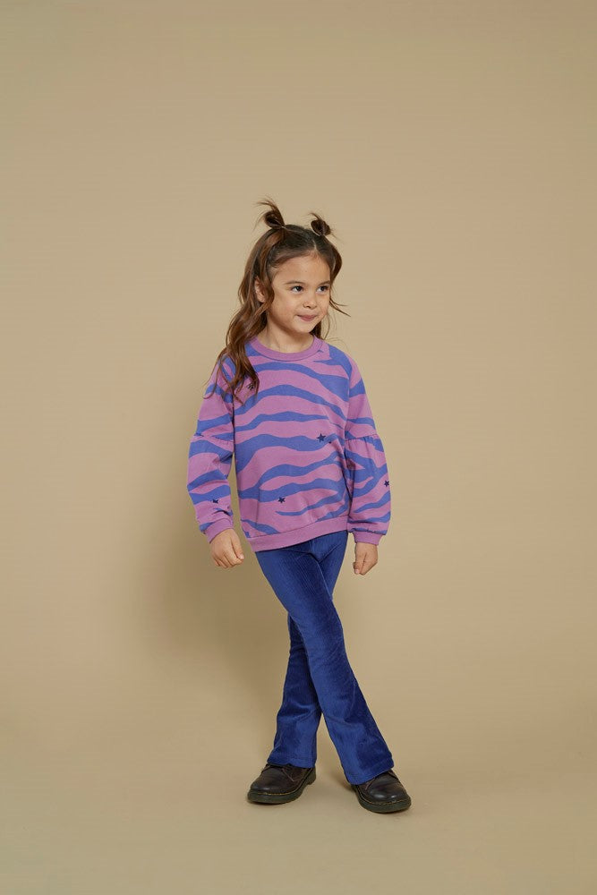 Kind draagt de Jubel Sweater AOP - Wild Soul in Violet met all-over print, in een avontuurlijke setting, Wintercollectie 2025.