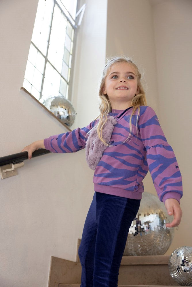 Kind draagt de Jubel Sweater AOP - Wild Soul in Violet met all-over print, in een avontuurlijke setting, Wintercollectie 2025.