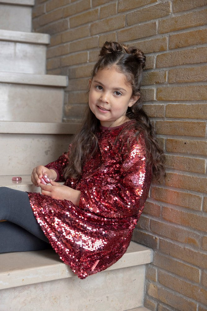 Jubel Pailetten Jurk - Queen Of Hearts Kind Poserend: "Kind poseert in de Jubel Pailetten Jurk - Queen Of Hearts in Bordeaux, met een feestelijke uitstraling en comfortabele pasvorm."