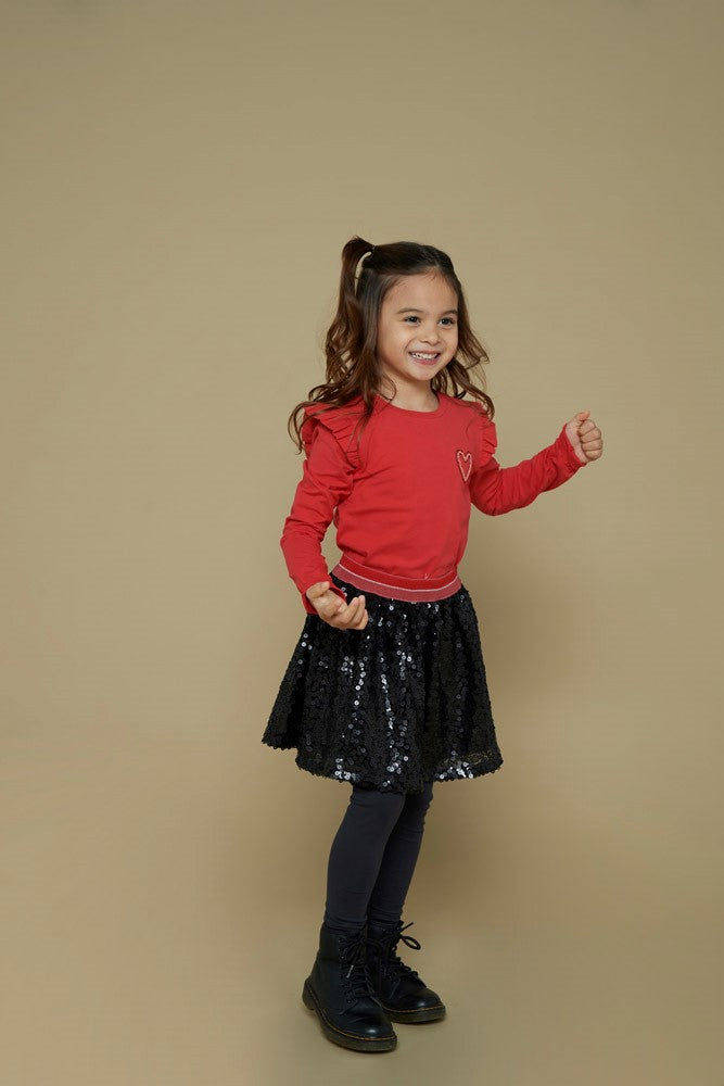 Jubel Longsleeve - Queen Of Hearts Sfeerfoto: "Kind draagt de Jubel Longsleeve - Queen Of Hearts in Rood, met een speelse hartprint, perfect voor een casual winteroutfit."