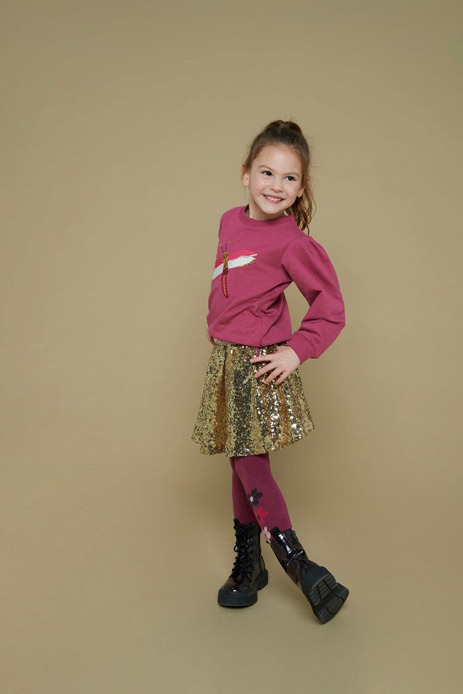 Jubel Pailetten Rok - Shine Bright Kind Poserend: "Kind poseert in de Jubel Pailetten Rok - Shine Bright, in Goud, met een sprankelende uitstraling en comfortabele pasvorm."