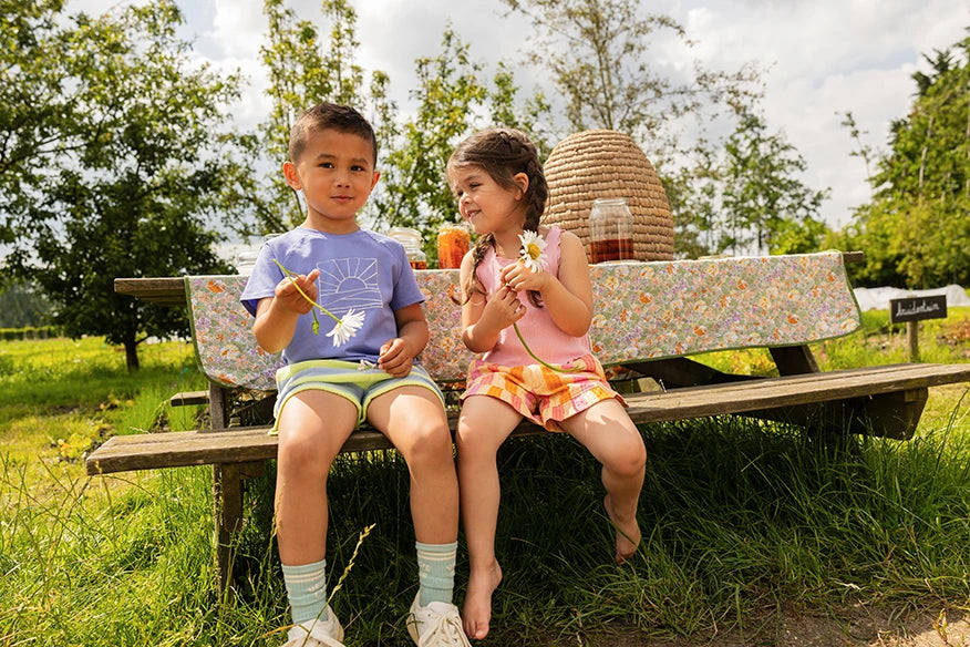 Jongen met een Sproet & Sprout Raglan T-Shirt Sunrise aan op bankje