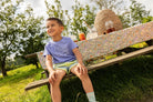 Jongen met een Sproet & Sprout Raglan T-Shirt Sunrise aan zit op bankje lacht