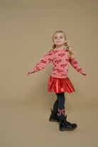 Jubel Sweater AOP - Queen Of Hearts Sfeerfoto: "Kind draagt de Jubel Sweater AOP - Queen Of Hearts in Lichtroze, met een speelse print van hartjes en strikjes, perfect voor casual winteroutfits."