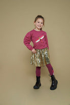 Jubel Pailetten Rok - Shine Bright Kind Poserend: "Kind poseert in de Jubel Pailetten Rok - Shine Bright, in Goud, met een sprankelende uitstraling en comfortabele pasvorm."
