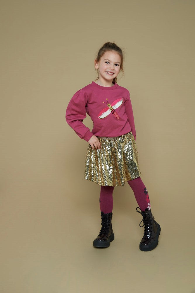 Jubel Pailetten Rok - Shine Bright Kind Poserend: "Kind poseert in de Jubel Pailetten Rok - Shine Bright, in Goud, met een sprankelende uitstraling en comfortabele pasvorm."